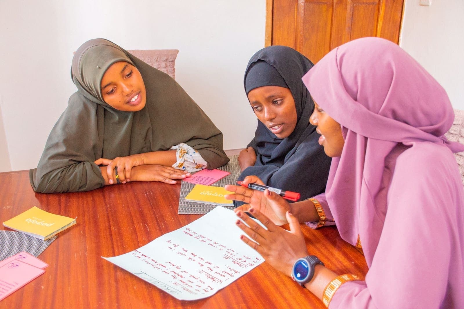 Three girls work together on an exercise at a table
